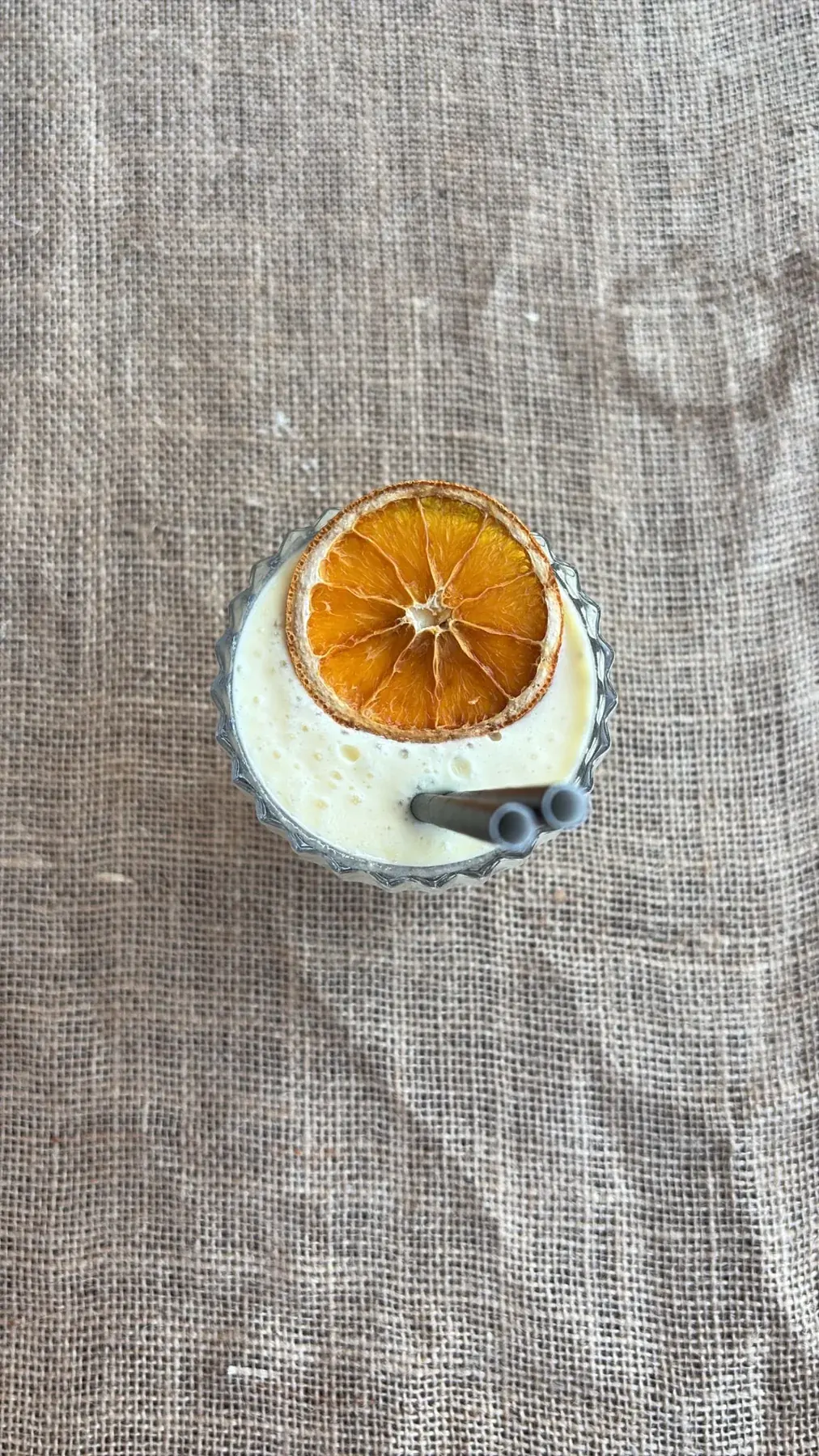 Glas met een gedroogd schijfje sinaasappel op een linnen tafelkleed