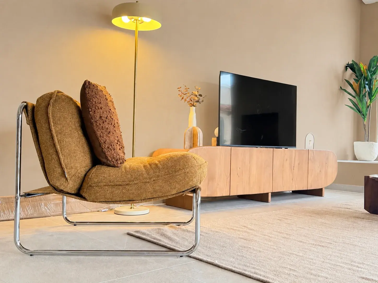 Designfauteuil met kussen naast het tv-meubel in de woonkamer